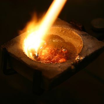 Flame heating metal in a refining crucible